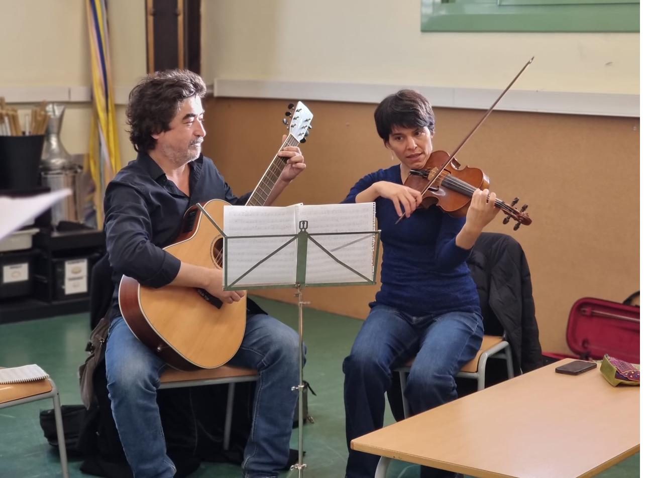 Dos familiars assajant: un a la guitarra i una al violí